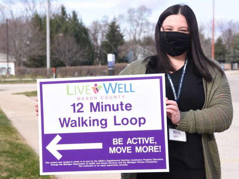 Erin Barrett holds a walking trail sign in Ludington.