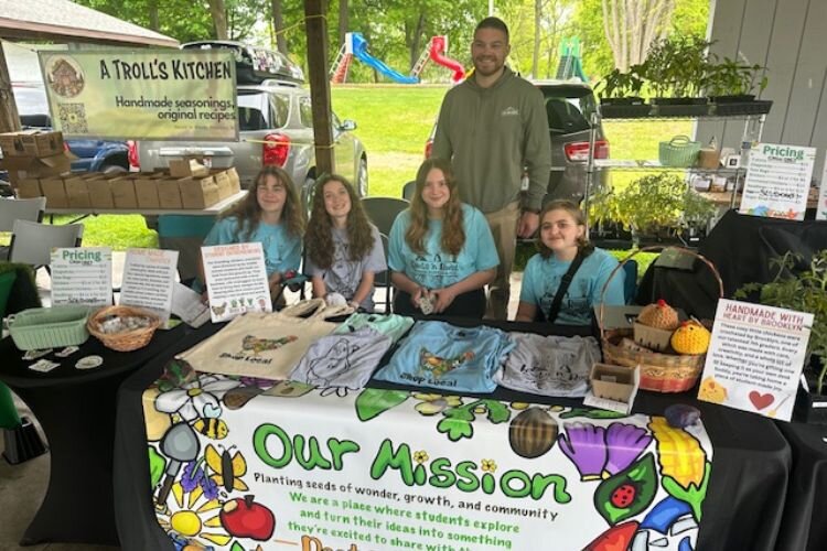 Dylan Banagis, owner of Life Unplugged, with the Roots ‘n Roost students at the Mt. Pleasant Farmers' Market on Thursday, May 29, 2025.