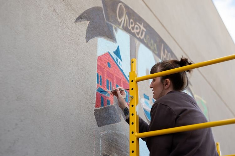 Artist Kayla Peake of KP Originals works on the mural in downtown Mt. Pleasant.