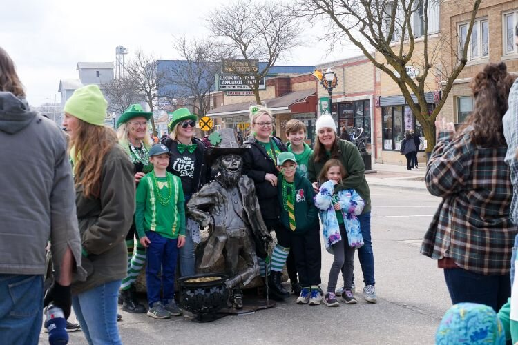 A group of festival goers pause for a photo opportunity with a leprechaun statue in downtown Clare at the Irish Festival on March 16, 2024. Photo Credit: Courtney Jerome / Epicenter Mt. Pleasant