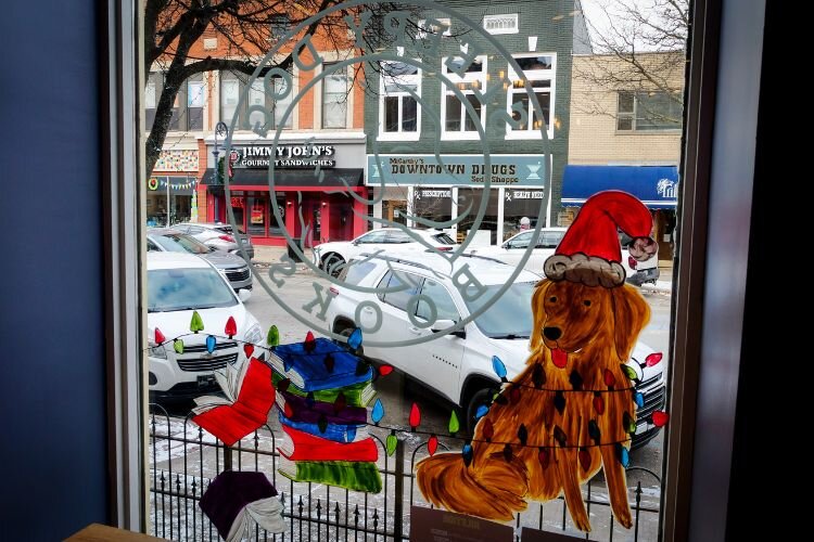 Artist Sara Woodruff painted holiday pups on the windows of Sleepy Dog Books downtown—it’s recommended to view these paintings from the inside, too! Photo Credit: Courtney Jerome / Epicenter Mt. Pleasant