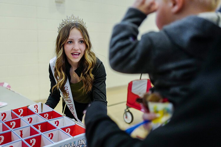 Maple Syrup Princess Bree of Shepherd, MI encourages a child playing a ball toss game at the Children’s Village in the Shepherd Elementary Gym in Shepherd, MI on Saturday, April 29, 2023. (Photo: Dan Gaken/Epicenter)