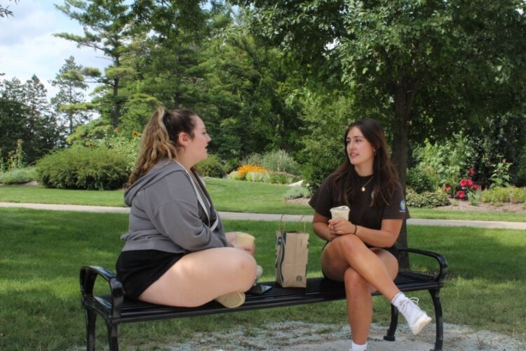 CMU freshmen Sophia Elgie, at left, a secondary education major, and Carmella Cortes, a finance major, settle on a park bench in the center of campus near Bovee University center for a sip and chat during freshmen move-in weekend. 
