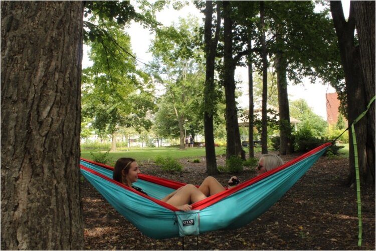 CMU seniors Lavender Bertsch, at left, elementary math education major, and Hannah Smock, integrated science major, spend a sunny Saturday hammocking in the center of campus in front of Bovee University Center as freshmen move into the dorms.