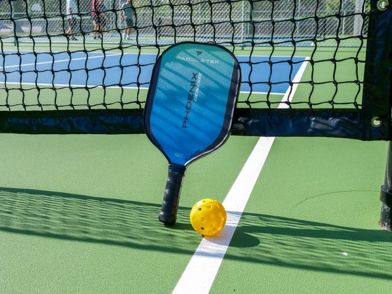 Pickleball is played with a racket and a wiffle-style ball.