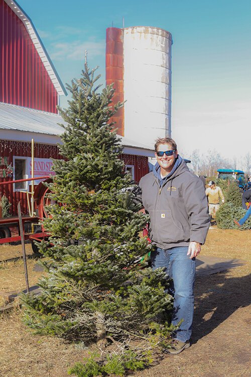 Mt. Pleasant resident Kent VanderLoon poses for a photo, showing off his freshly-cut Christmas tree for this year's holiday.