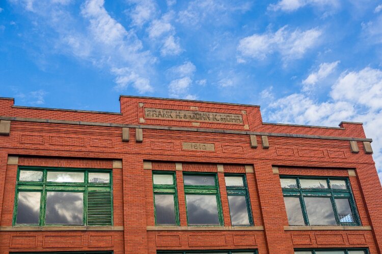 The Mohr building has a minor facade and a stone tablet with “F.H. & J.K. Mohr Block 1912” at the top of it facing Midland Street. 