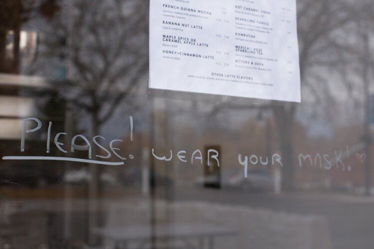 A note is written on the door at Pleasant City Coffee asking patrons to wear a mask.