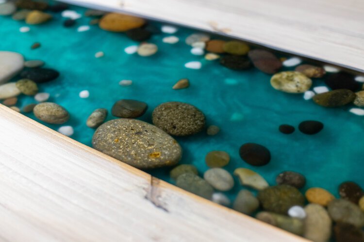 A river runs through the dining table Johnston is working on. Johnston says he will occasionally invite clients in to provide creative insight to their projects, and the client who commissioned this piece placed the rocks within the river.