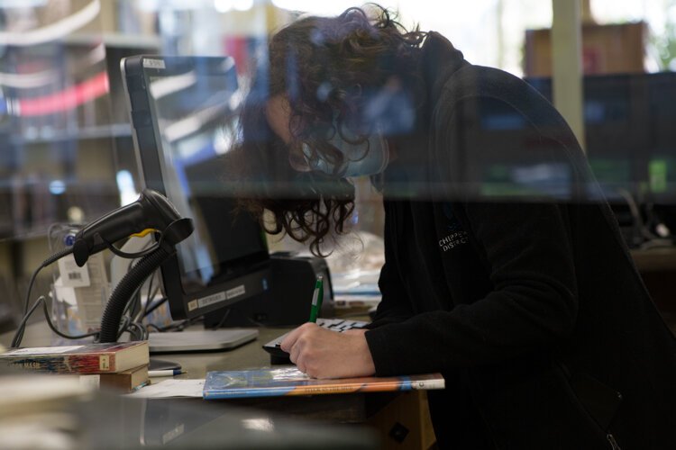 Protective plastic wraps around the Customer Service desk where Veterans Memorial Library employee Karylnn Madison works.