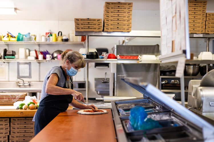 Shepherd resident Linnette Klump, 54, spreads sauce on pizza dough at Grandma Esther’s Kitchen. Just minutes later, Klump places the prepared pie in the establishment’s 90-year-old oven.  “[The diner] is out here in the community, in the middle of nowhere and it’s easy, convenient, being local. Mary and Joe [Ramon] are great people to work for,” Klump says. 