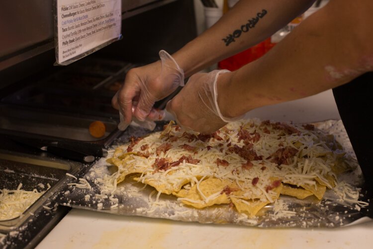 Vin Trofeo's kitchen worker Jason Stevens makes an order of baked nachos.