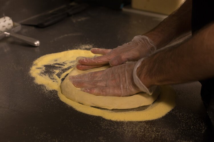 A Vin Trofeo's kitchen worker shapes the freshly-made pizza dough. Being able to make your own dough can be a really great thing," says Baird. "Dough can get very expensive when you buy it, and can be very cost effective when you make it. But then you have to factor in your time and labor. We never claimed to have the cheapest pizza in town because we don't want to be cheap pizza."