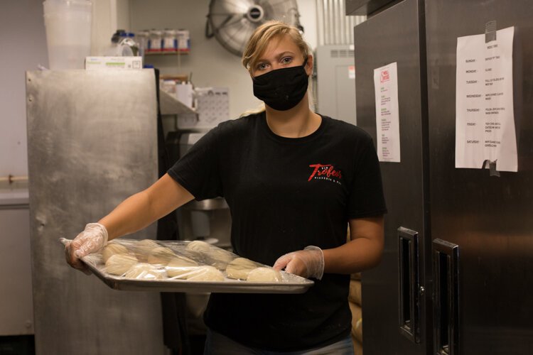 Vin Trofeo's kitchen worker Jess Acker puts away the pizza dough to allow it to proof.
