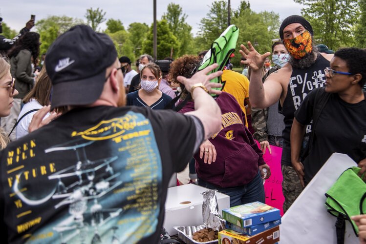 Organizer Steven Green throws a vest to John Campbell, who volunteered as a peace moderator for an event to protest the death of George Floyd and social injustice June 1 outside the Bovee University Center in Mt. Pleasant, MI.