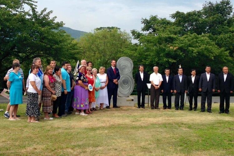The City of Mt. Pleasant presents a sculpture, created by local artist Colette Phillips, to celebrate the 50th anniversary of the Sister City relationship at Friendship Park in Okaya, Japan in 2015. On the right are Okaya Mayor Ryugo Imai and members of the Okaya City Council. On the left are Mayor Jim Holton and his wife Karen, former mayors Bruce Kilmer, Cindy Kilmer, and Kathy Ling, Judy Pamp representing the Saginaw Chippewa Tribe, and 13 other Mt. Pleasant representatives.