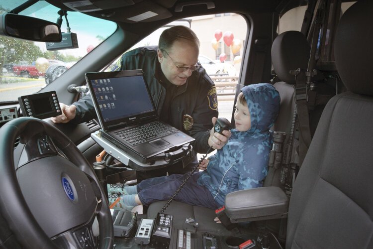Central Michigan University Police Department's Chief of Police Larry Klaus shows 4-year-old Tobi Marcinek how to work a squad car's radio during CMUPD's 50th anniversary celebration.