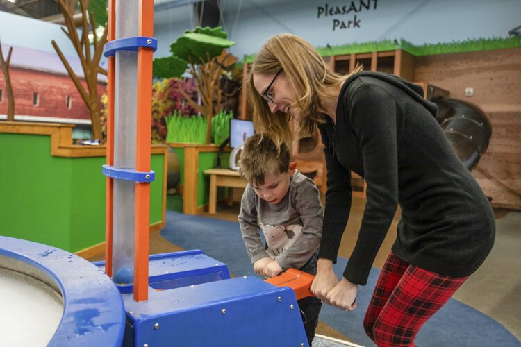 Alma College Head Start Program parent, Wendy Perrier, helps her son Eli increase air pressure at the "Water Works, Inc." exhibit at the Mount Pleasant Discovery Museum.