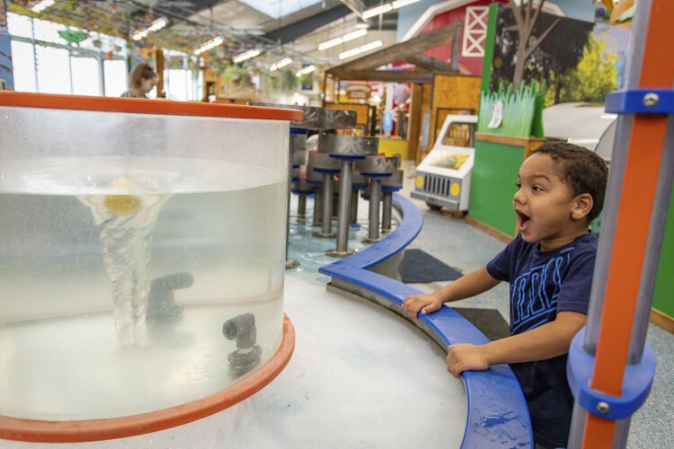 An Alma College Head Start Program preschooler reacts to losing his ball in a waterspout at the "Water Works, Inc." exhibit. The exhibit aims to teach children about the way water moves over and around solid objects.