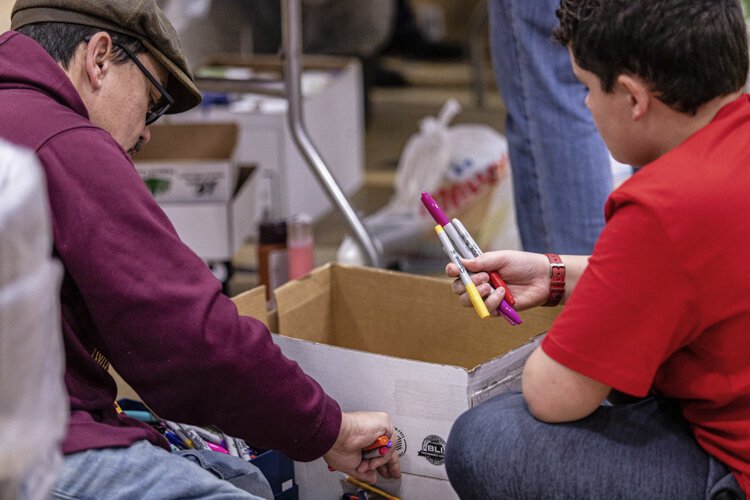 Mount Pleasant resident Jerry DiMaria, 46, and his son Lukas, 12, organize writing utensils for stockings while volunteering for Christmas Outreach Dec. 3 at Finch Fieldhouse on Central Michigan University's campus. DiMaria's wife, Claire, 47, also helped organize items for stockings.