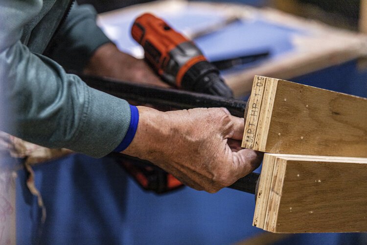 Mount Pleasant resident Ray Johnson, 81, adjusts the height of a coat rack at Christmas Outreach Dec. 3 at Finch Fieldhouse on Central Michigan University's campus.