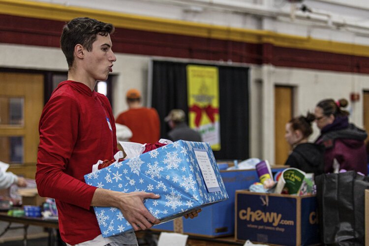 Sacred Heart Academy student Michael Hopp, 18, carries holiday items to a distribution table Dec. 6 at Finch Fieldhouse on Central Michigan University's campus. Hopp is one of 32 volunteers from Sacred Heart Academy that helped during the Dec. 6 distribution period.
