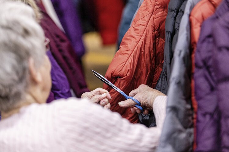 Mount Pleasant resident Jan Johnson, 77, cuts tags off of winter jackets donated to Christmas Outreach Dec. 3 at Finch Fieldhouse on Central Michigan University's campus.