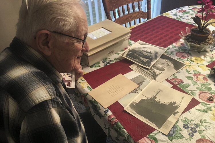 Henry Meabrod Sr. looks at memorabilia from his time in the Navy during WWII.
