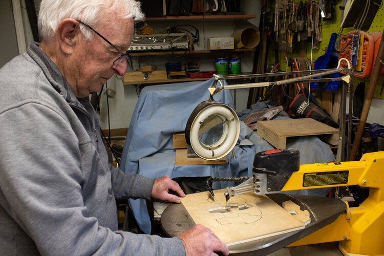 Don Hire, who serves as Secretary of the Mid-Michigan Woodcrafters Club, cuts out a puzzle that will be given to charity at Christmas.