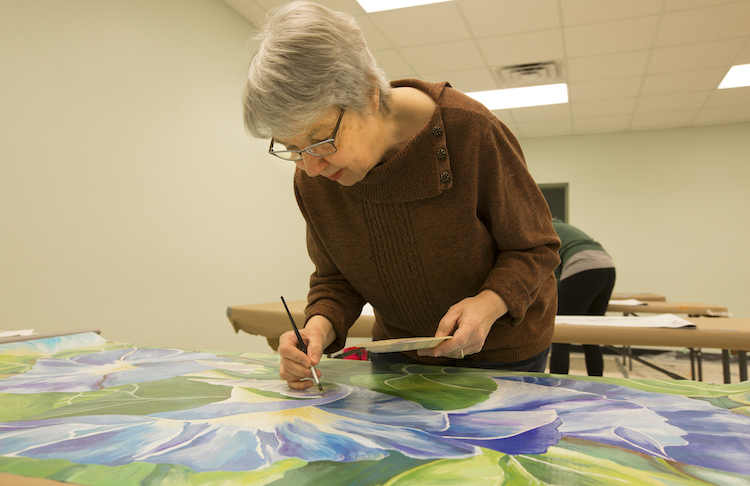 Peggy Brisbane works on her banner at Jamieson Hall Union Township in Mt. Pleasant on Thursday, March 21, 2019. Brisbane's banner is of morning glories, inspired by a flower she grows in her home garden.