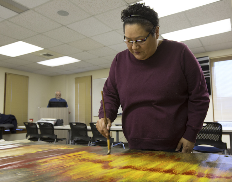 Paula Chippewa works on painting her banner during class at the Saginaw Chippewa Tribal College on Tuesday, March 26, 2019. 