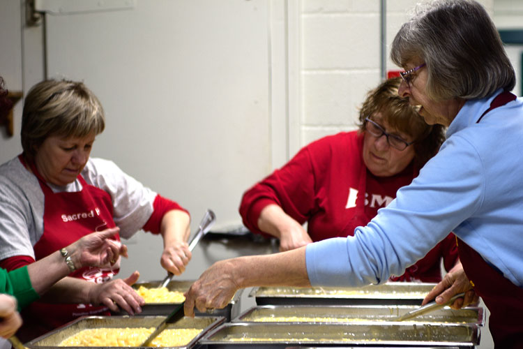 Volunteers work together to prepare Macaroni and Cheese on the morning of Friday, April 11