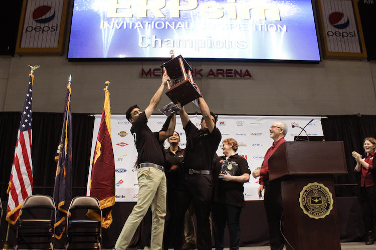 Dart Team 1 team mates Bernad Nelson and Manjunath Madarampalli hoist their teamâs trophy in the air after they received first place in the championship round of the 7th Annual ERPsim Invitational Competition