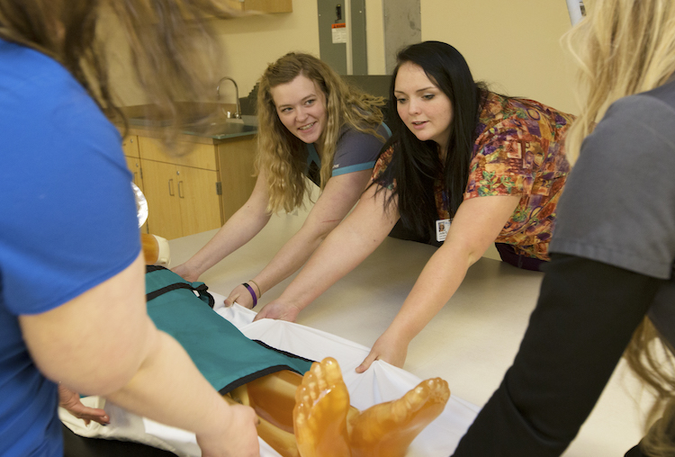 Mid Michigan College students Jessica Osentoski and Jessica Claffey pitch in to help move the anthropomorphic full body phantom onto the x-ray table during class.