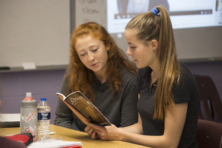 Christine Evans, 18, and Scout Nelson, 18, share a book needed for an assignment during class on Monday, Oct. 8, 2018. Evans and Nelson are both seniors at Sacred Heart Academy Catholic school and are in their fourth year of Spanish classes.