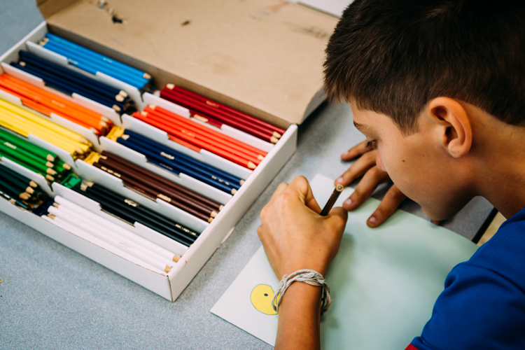A PEAK student colors with pencils