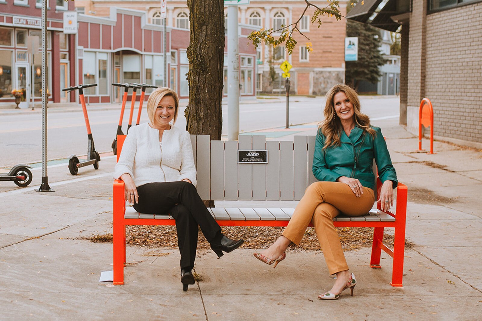 Grand Rapids Mayor Rosalynn Bliss and AARP Michigan Associate State Director Jennifer Feuerstein sit on one of the new benches in Creston.