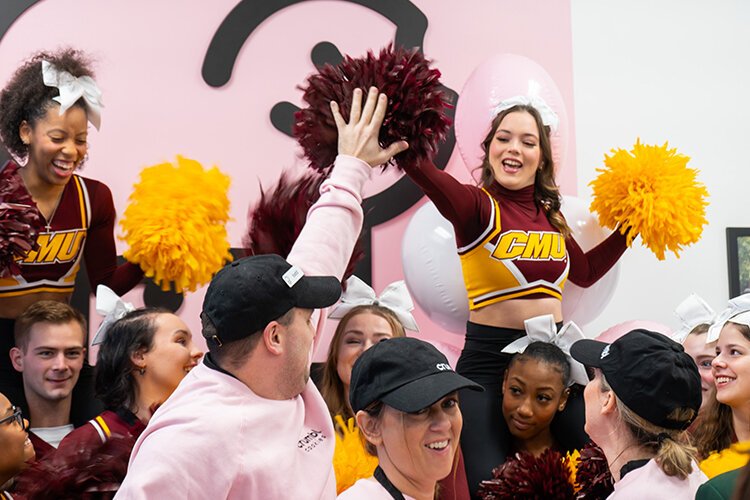 Mt. Pleasant Crumbl Cookies co-owner Todd Korneoely high-fives a Central Michigan University cheer squad member during the ribbon cutting celebration. (Photo: Addy Wachter/Epicenter)