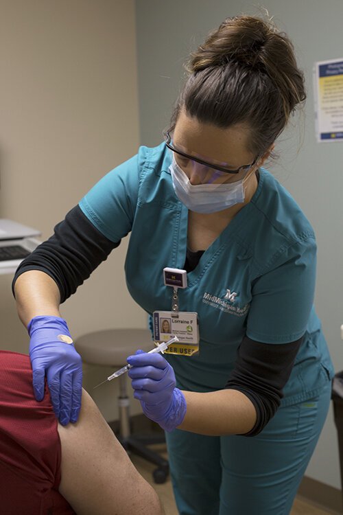 Certified medical assistant Lorraine Farkas administers Pfizer's COVID-19 vaccine to a patient.